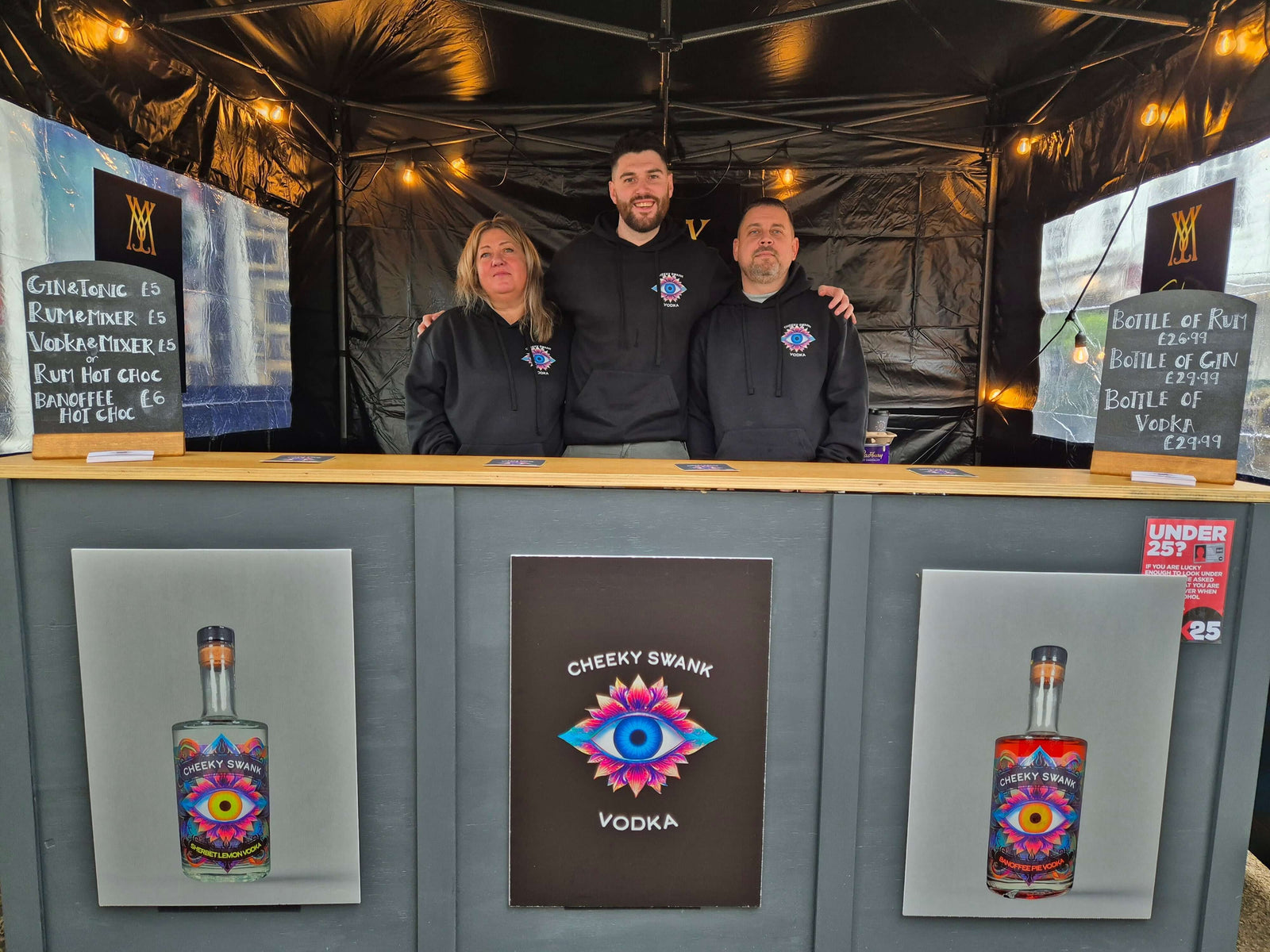 Three friends at a Cheeky Swank Vodka booth showcasing their unique vodka and vibrant branding.